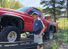 Pegasus crew member standing beside a red pickup on the flatbed
